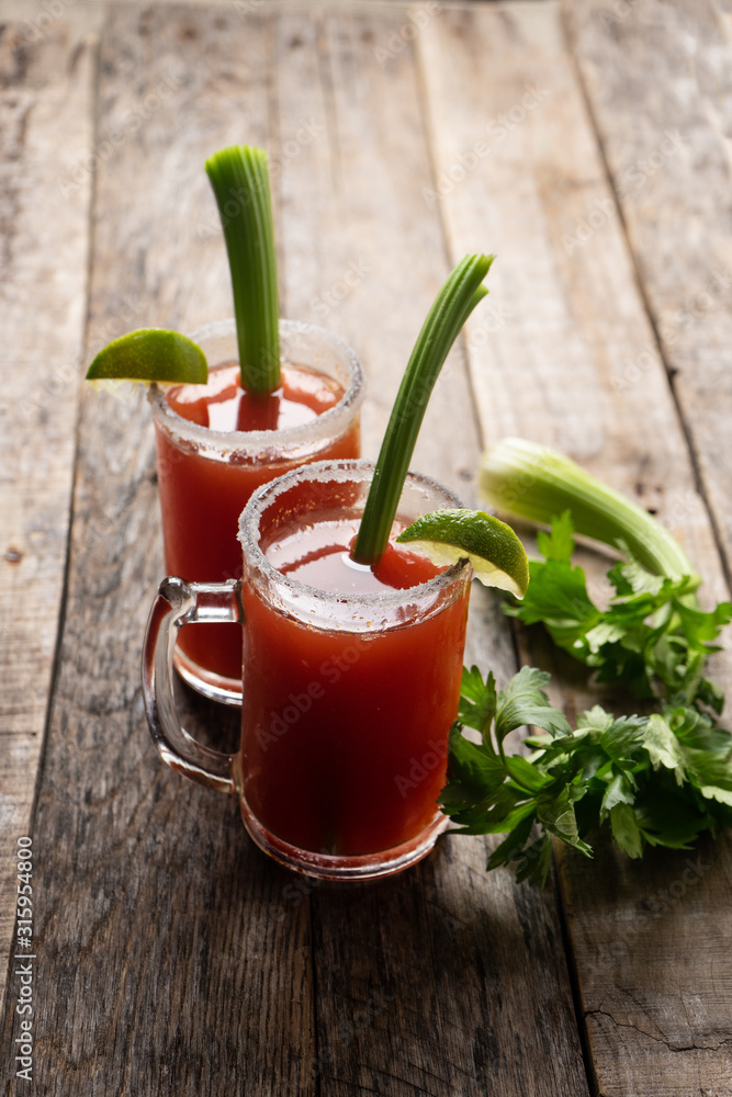 Mexican beer cocktail called michelada with celery on wooden background Mexican beer cocktail called michelada with celery on wooden background