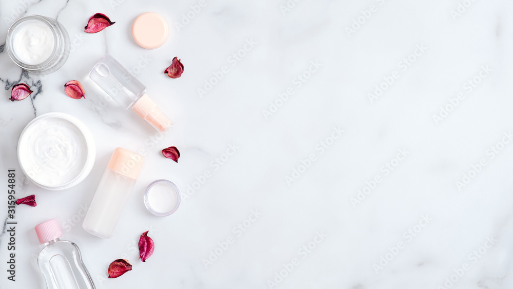 Herbal hand cosmetic cream and lotion bottle with pink flower petals on marble background. Flat lay, top view, copy space. Hand skin care, organic beauty products concept Herbal hand cosmetic cream and lotion bottle with pink flower petals on marble background. Flat lay, top view, copy space. Hand skin care, organic beauty products concept