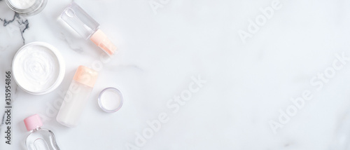 Beauty blog banner with cosmetic cream and lotion bottles on marble background. Top view, flat lay, copy space. Hand skin care, spa cosmetic products concept