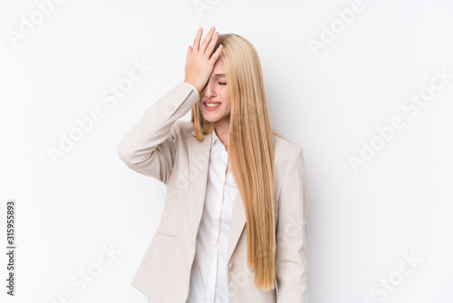 Young business blonde woman on white background forgetting something, slapping forehead with palm and closing eyes.