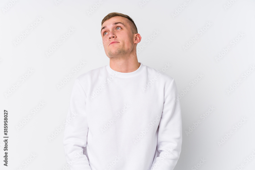 Young caucasian man on white background dreaming of achieving goals and purposes Young caucasian man on white background dreaming of achieving goals and purposes