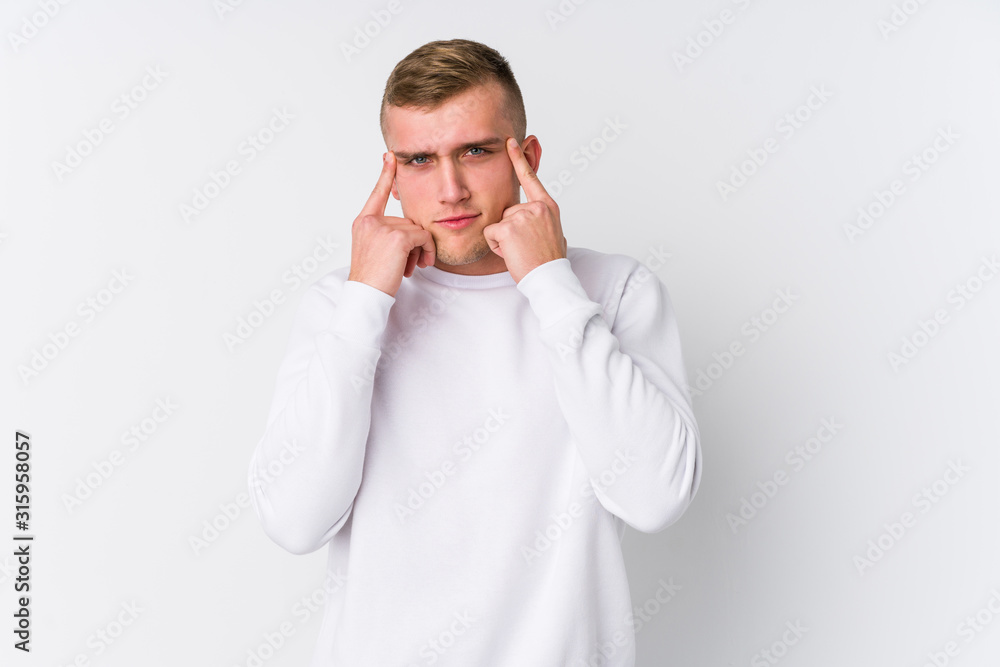 Young caucasian man on white background focused on a task, keeping forefingers pointing head. Young caucasian man on white background focused on a task, keeping forefingers pointing head.
