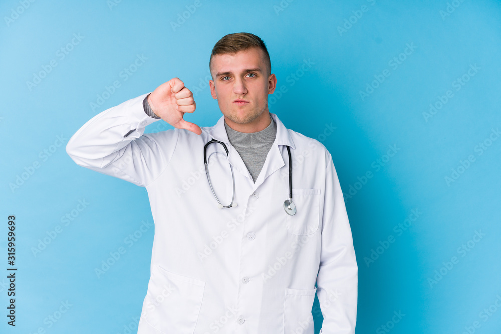 Young caucasian doctor man showing a dislike gesture, thumbs down. Disagreement concept. Young caucasian doctor man showing a dislike gesture, thumbs down. Disagreement concept.