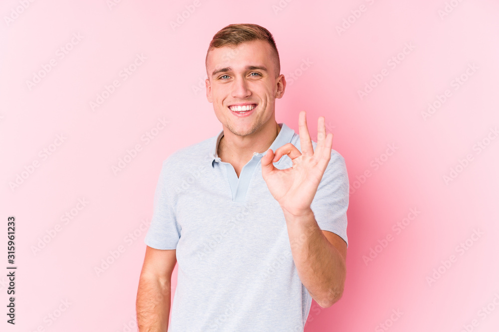Young caucasian man isolated cheerful and confident showing ok gesture.