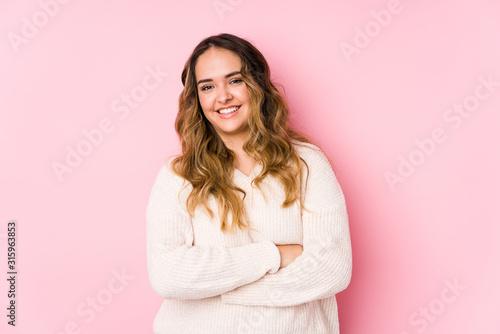 Young curvy woman posing in a pink background isolated laughing and having fun. photo