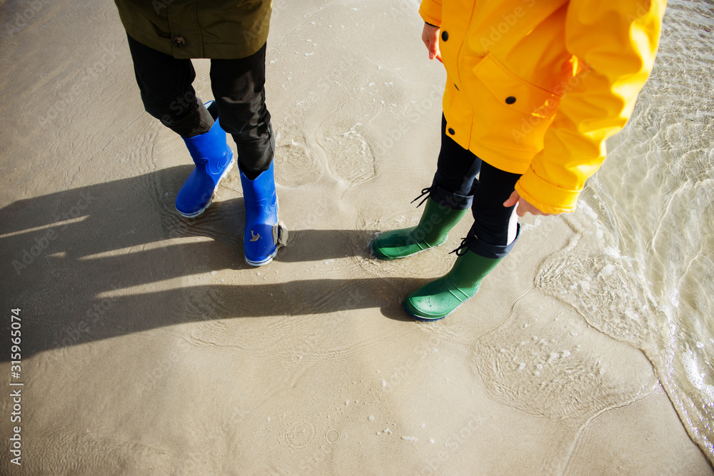 Two children standing im water of cold Baltic sea in rubber high boots foto  de Stock | Adobe Stock