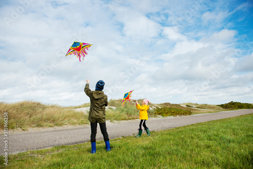 Happy siblings children running and having fun with kite on beach