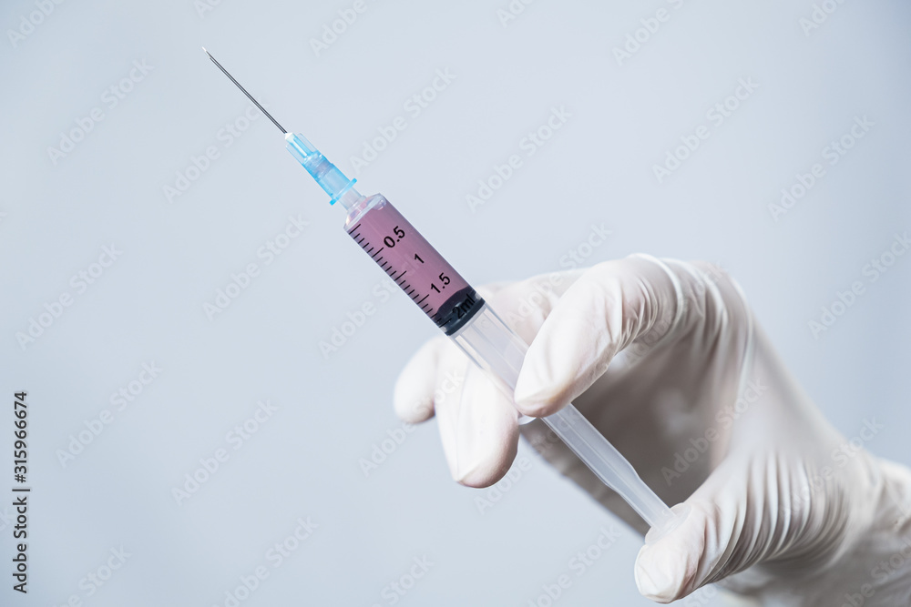 Injection ready for application in doctor's hand. Hand in glove holding a syringe with intravenous injection, concept of medical treatment Injection ready for application in doctor's hand. Hand in glove holding a syringe with intravenous injection, concept of medical treatment