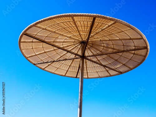 Straw sunshade in sunny summer day  tropical background.