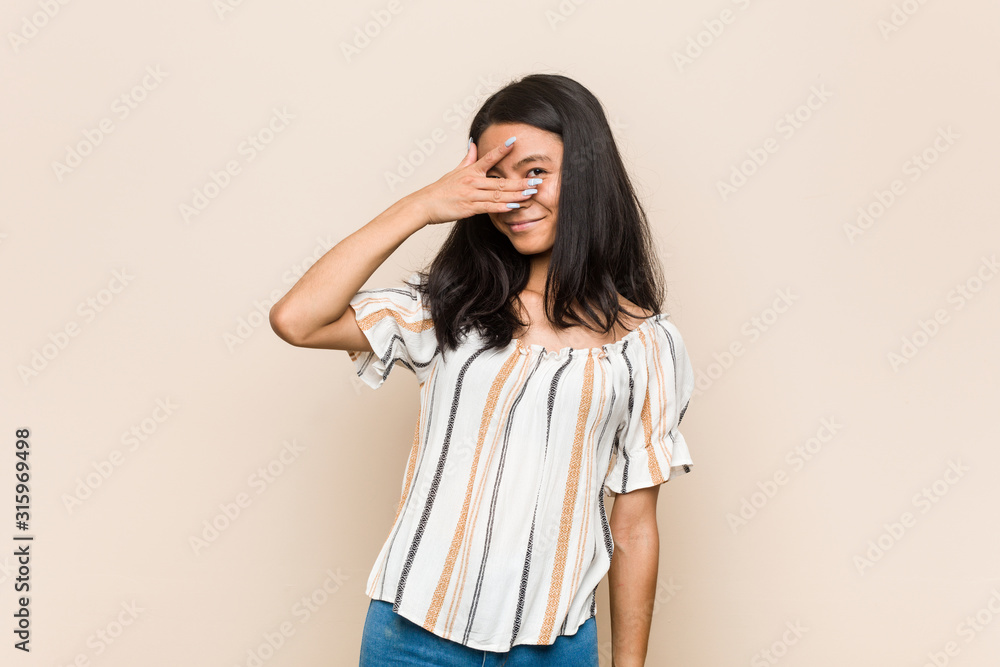 Young cute chinese teenager Young blonde woman wearing a coat against a pink background blink at the camera through fingers, embarrassed covering face. Young cute chinese teenager Young blonde woman wearing a coat against a pink background blink at the camera through fingers, embarrassed covering face.