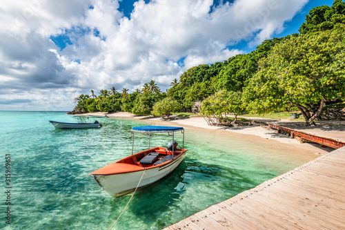 Small motorized boat at the pier and beach of Cayo Levantado Island, Samana Bay, Dominican Republic. photo