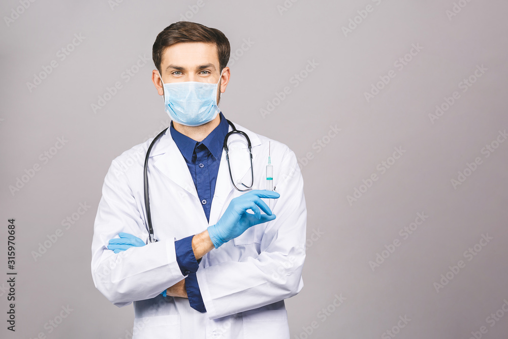 Standing doctor raising an injection puts the mask on mouth hang the stethoscope around neck in a white uniform, isolated on a grey background. Standing doctor raising an injection puts the mask on mouth hang the stethoscope around neck in a white uniform, isolated on a grey background.