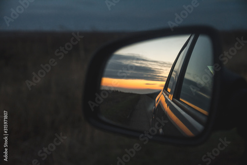 Colors of sunset in the rear view mirror of a car