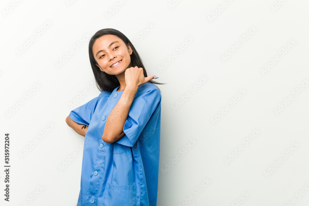 Young asian nurse woman points with thumb finger away, laughing and carefree. Young asian nurse woman points with thumb finger away, laughing and carefree.