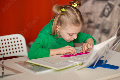little pretty girl with poor posture, slouching, 7-8 years old, first grader, at her desk, doing homework, teaching lessons, drawing on the line
