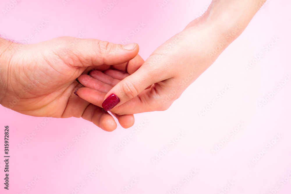 Two gentle hands male and female on a pink background close-up. Two gentle hands male and female on a pink background close-up.