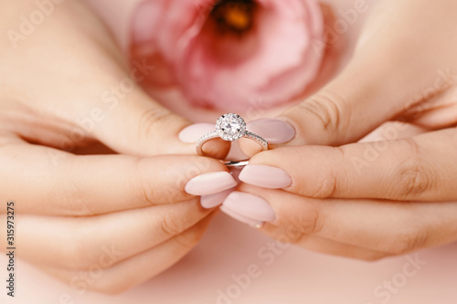 Close up of woman's hand holding elegant diamond ring.