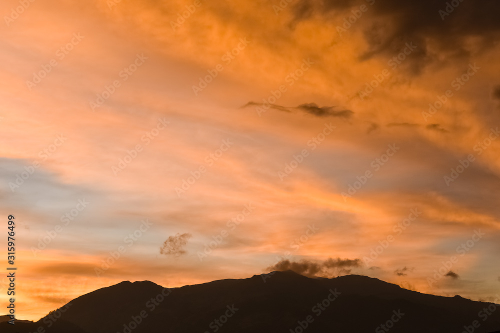 Blue sky with orange clouds over the silhouette of a mountain