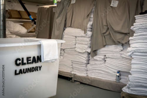 Huge main laundry on the cruise ship with a lot of clean linen and towels. White trolley with sign is full of clothes. 