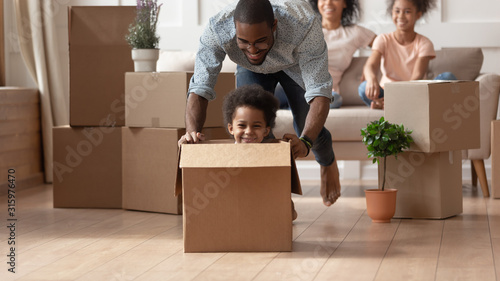 Laughing black little son playing with happy father.