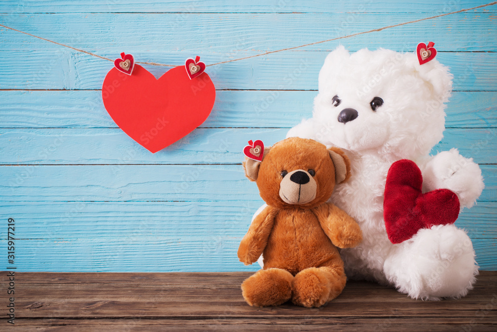 Obraz premium Teddy bear with red heart on old wooden background. Valentine's