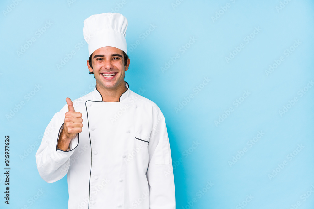 Young cook man isolated smiling and raising thumb up Young cook man isolated smiling and raising thumb up