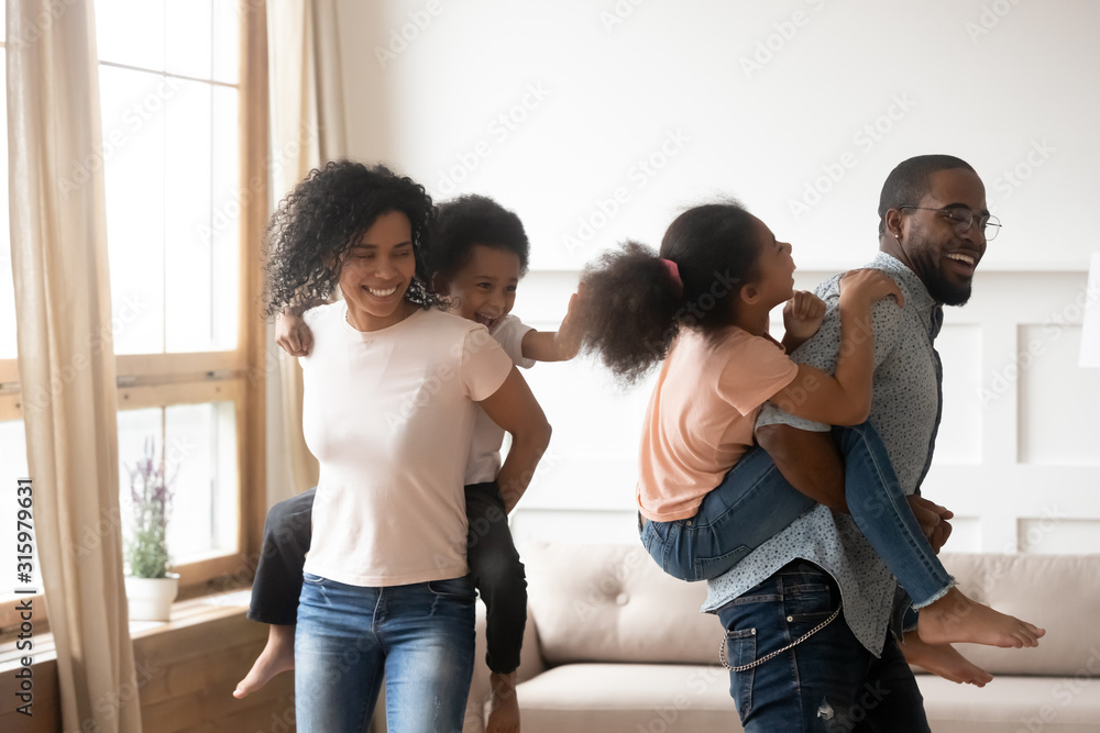 Happy black couple playing with kids on backs. Happy black couple playing with kids on backs.