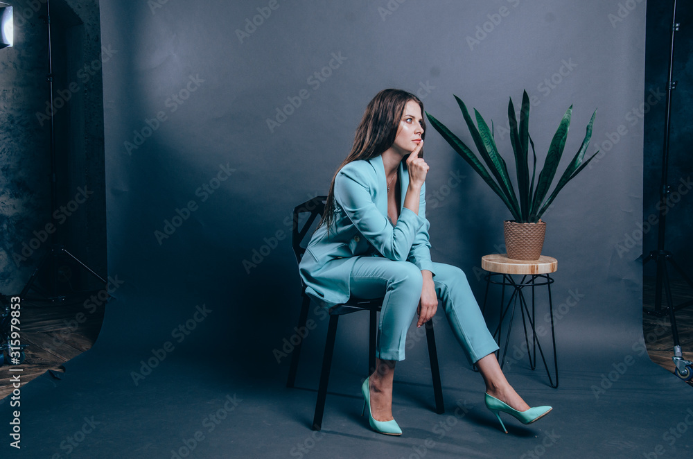 Portrait of young woman in blue suit. Studio shot on grey Portrait of young woman in blue suit. Studio shot on grey