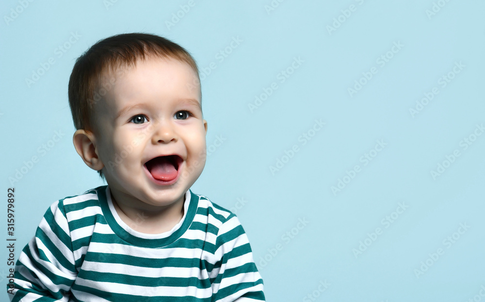 Portrait of a cute toddler 1 year old in a striped jacket on a blue background, rejoices laughing after seeing his mother. Portrait of a cute toddler 1 year old in a striped jacket on a blue background, rejoices laughing after seeing his mother.