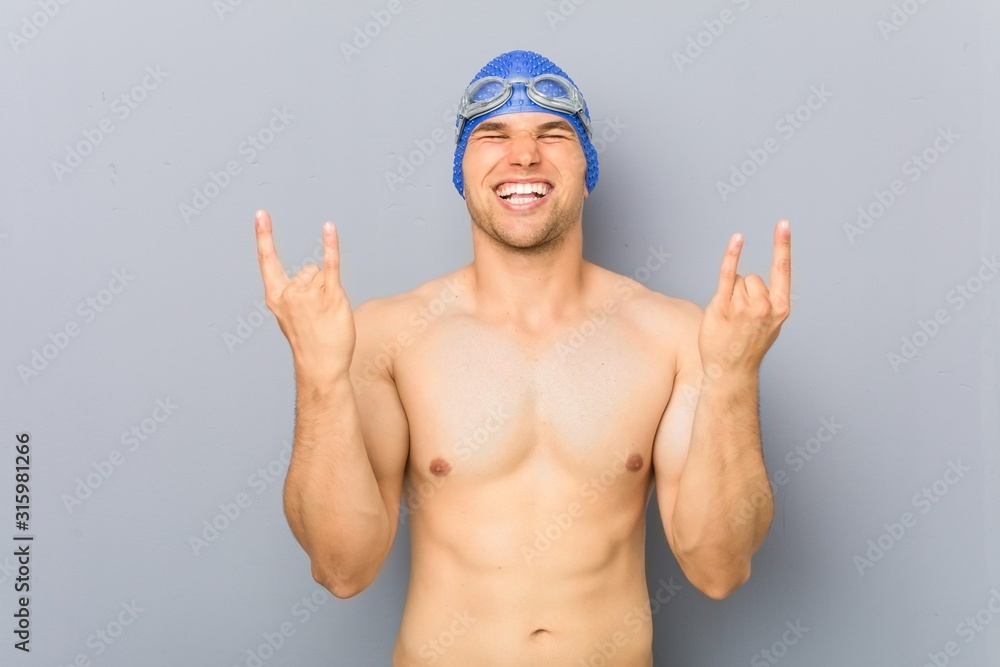 Young professional swimmer man showing rock gesture with fingers