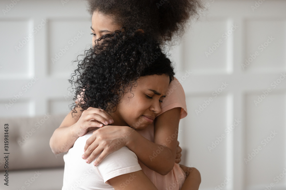 Obraz premium Close up sad upset black woman cuddling daughter.