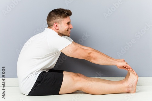 Young caucasian man stretching practicing yoga.