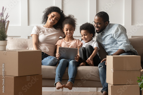 Happy black family sitting in living room with computer.