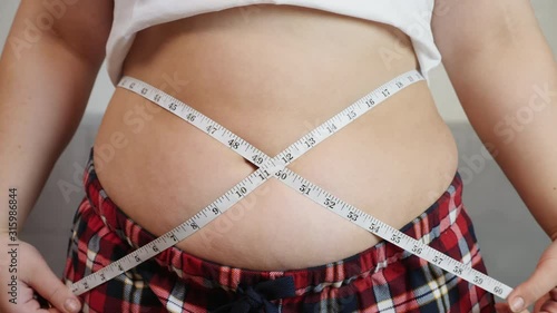 Overweight, fat woman measuring her stomach, close-up shot photo
