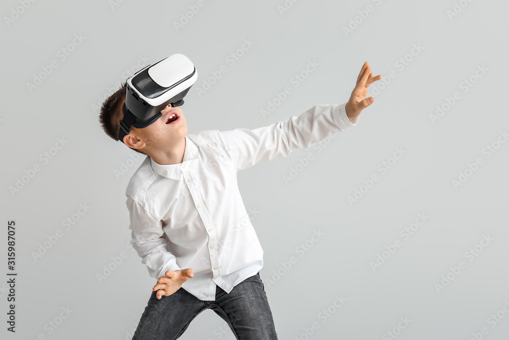 Little boy with virtual reality glasses on grey background Little boy with virtual reality glasses on grey background