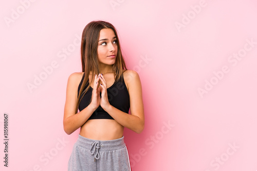 Young caucasian fitness woman posing in a pink background making up plan in mind  setting up an idea.