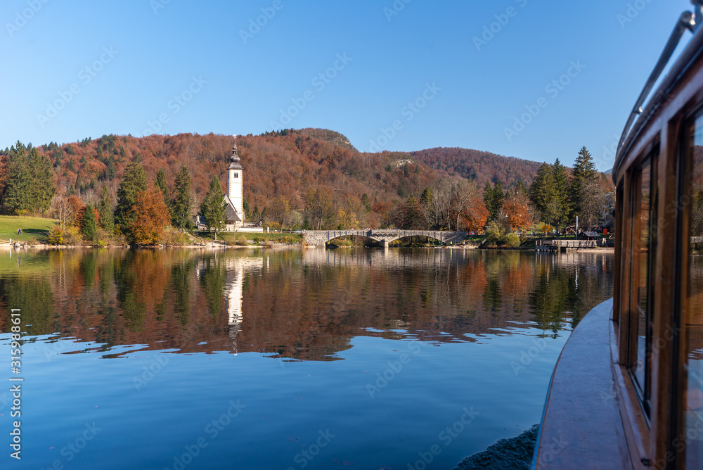 Fototapeta premium Church of Sv. John the Baptist and a bridge by the Bohinj lake in winter, Slovenia