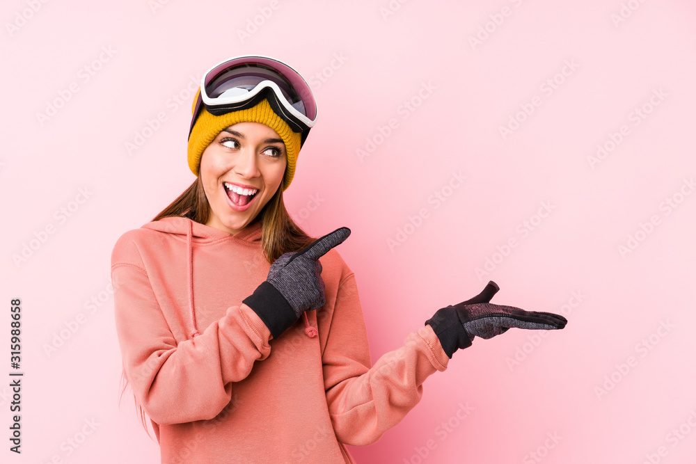 Young caucasian woman wearing a ski clothes isolated excited holding a copy space on palm. Young caucasian woman wearing a ski clothes isolated excited holding a copy space on palm.