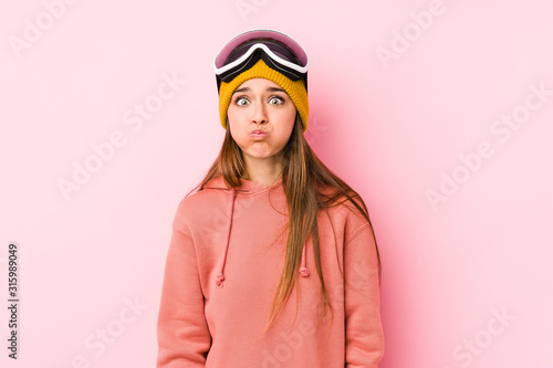 Young caucasian woman wearing a ski clothes isolated blows cheeks, has tired expression. Facial expression concept.