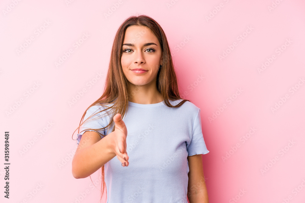 Young caucasian woman wearing a ski clothes isolated stretching hand at camera in greeting gesture. Young caucasian woman wearing a ski clothes isolated stretching hand at camera in greeting gesture.