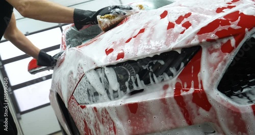 Manual wash for perfect clean car. Cleaning car using high pressure water, Man cleaning vehicle with high pressure water spray or jet. Car wash details, Close up concept. 
