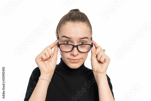 serious looking woman holds down the glasses and looks over the glasses