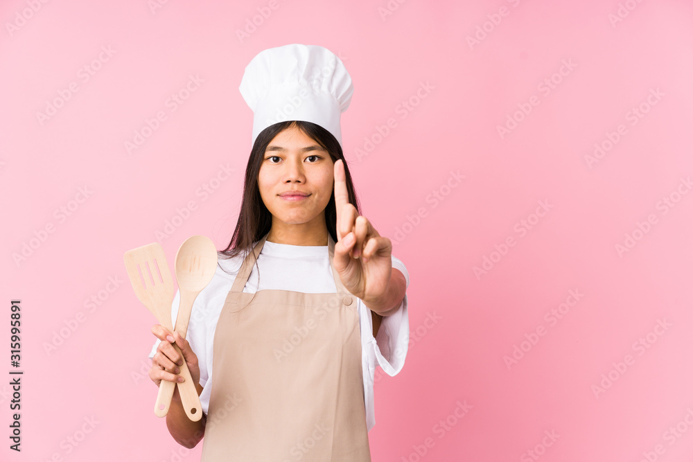 Young chinese chef woman isolated showing number one with finger. Young chinese chef woman isolated showing number one with finger.