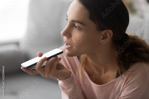 Fotografie Close up thoughtful young lady dictating audio message.