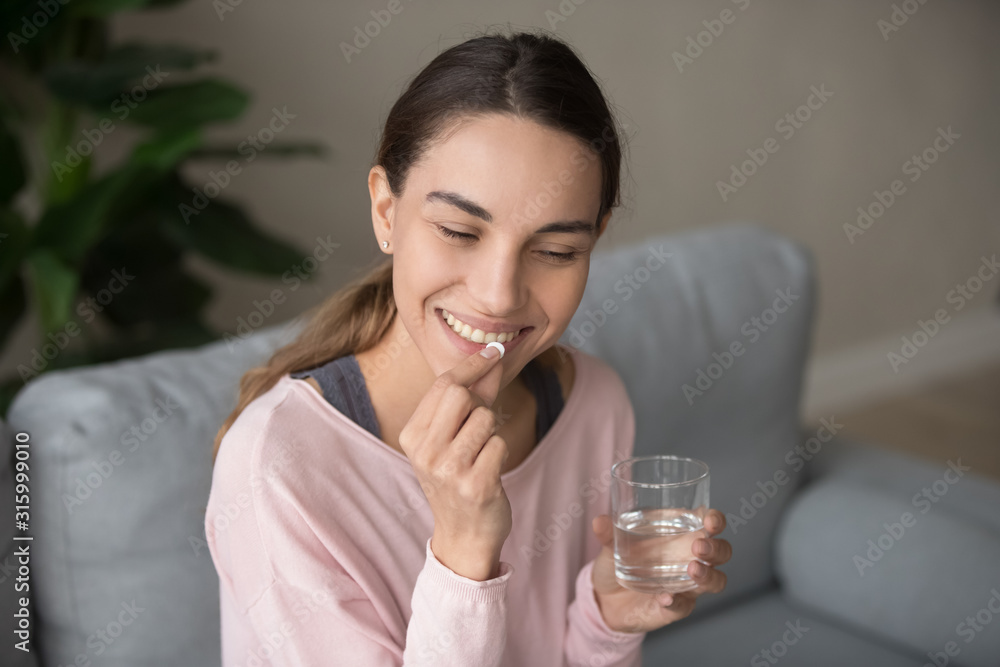 Smiling happy millennial woman taking daily vitamins. Smiling happy millennial woman taking daily vitamins.