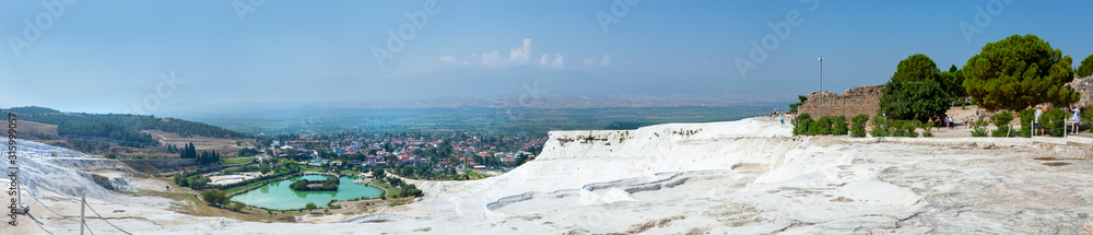Panorama of the unique Pamukkale natural complex with white cliffs, an emerald lake, a picturesque village, ancient ruins and a beautiful valley.