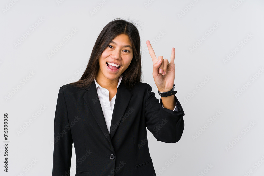 Young asian business woman showing a horns gesture as a revolution concept. Young asian business woman showing a horns gesture as a revolution concept.