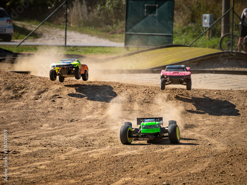 Three offroad RC cars racing on a track 