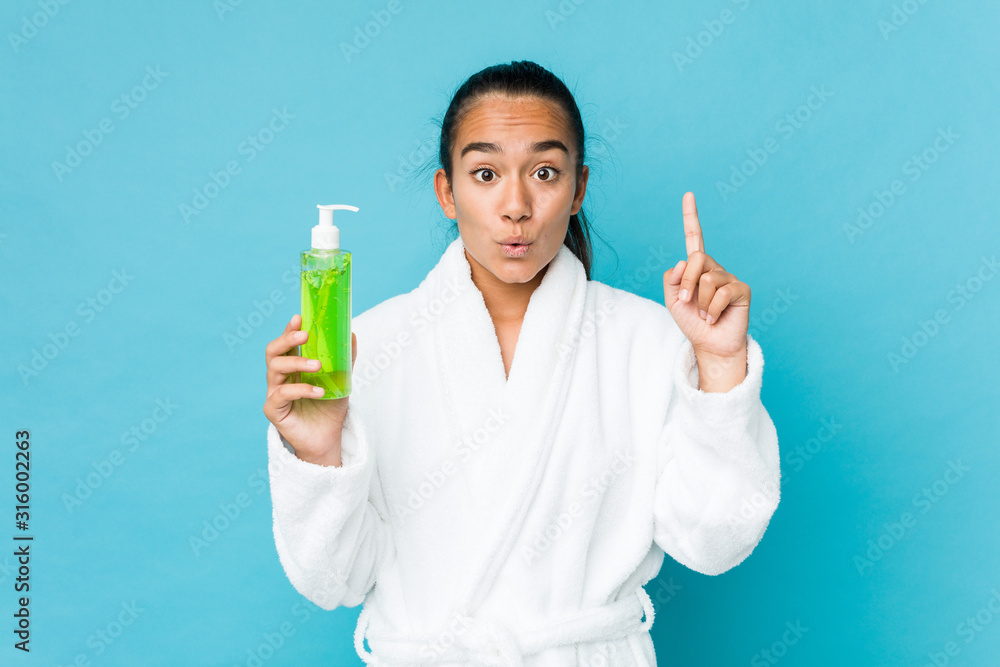 Young mixed race indian holding an aloe vera bottle having some great idea, concept of creativity. Young mixed race indian holding an aloe vera bottle having some great idea, concept of creativity.