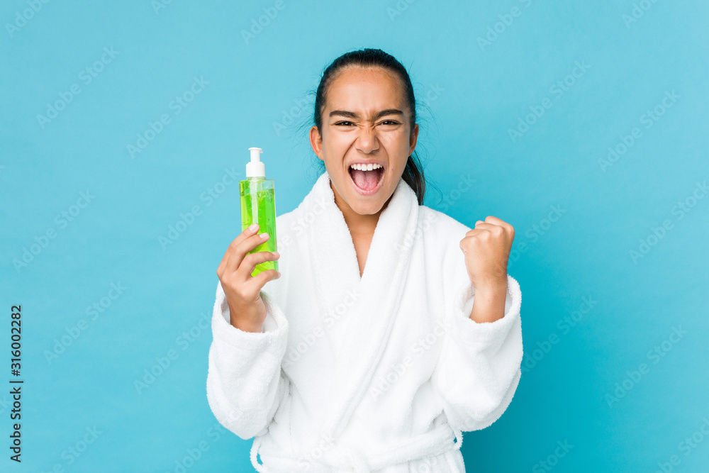 Young mixed race indian holding an aloe vera bottle cheering carefree and excited. Victory concept. Young mixed race indian holding an aloe vera bottle cheering carefree and excited. Victory concept.